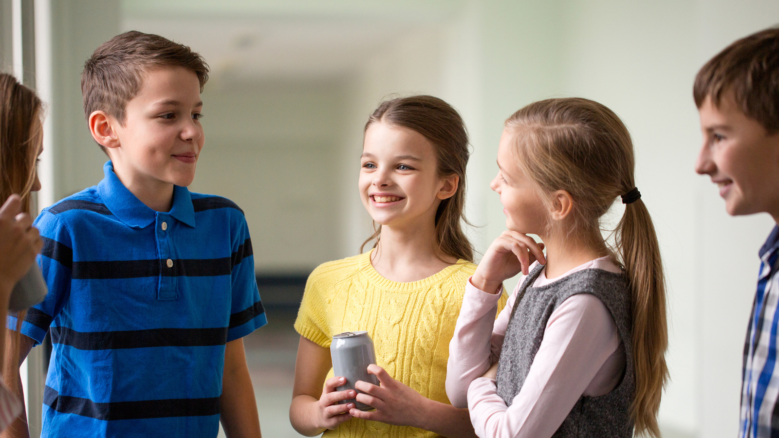 5 school-aged children chatting in a corridor