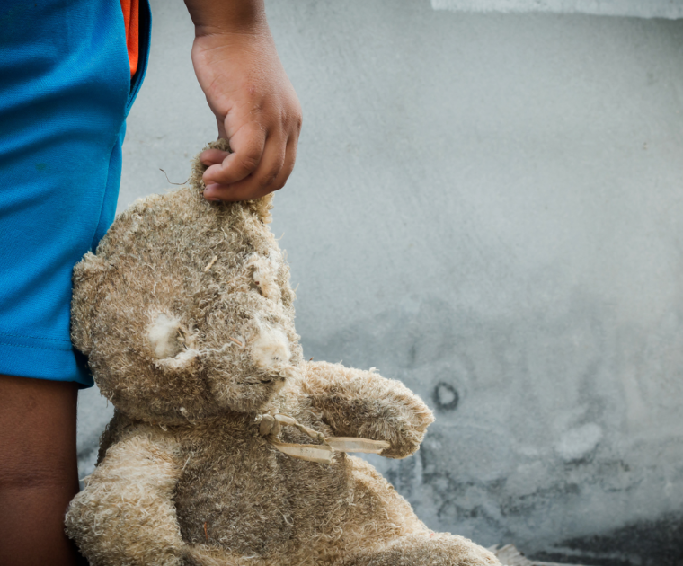 Child holding a worn teddy bear