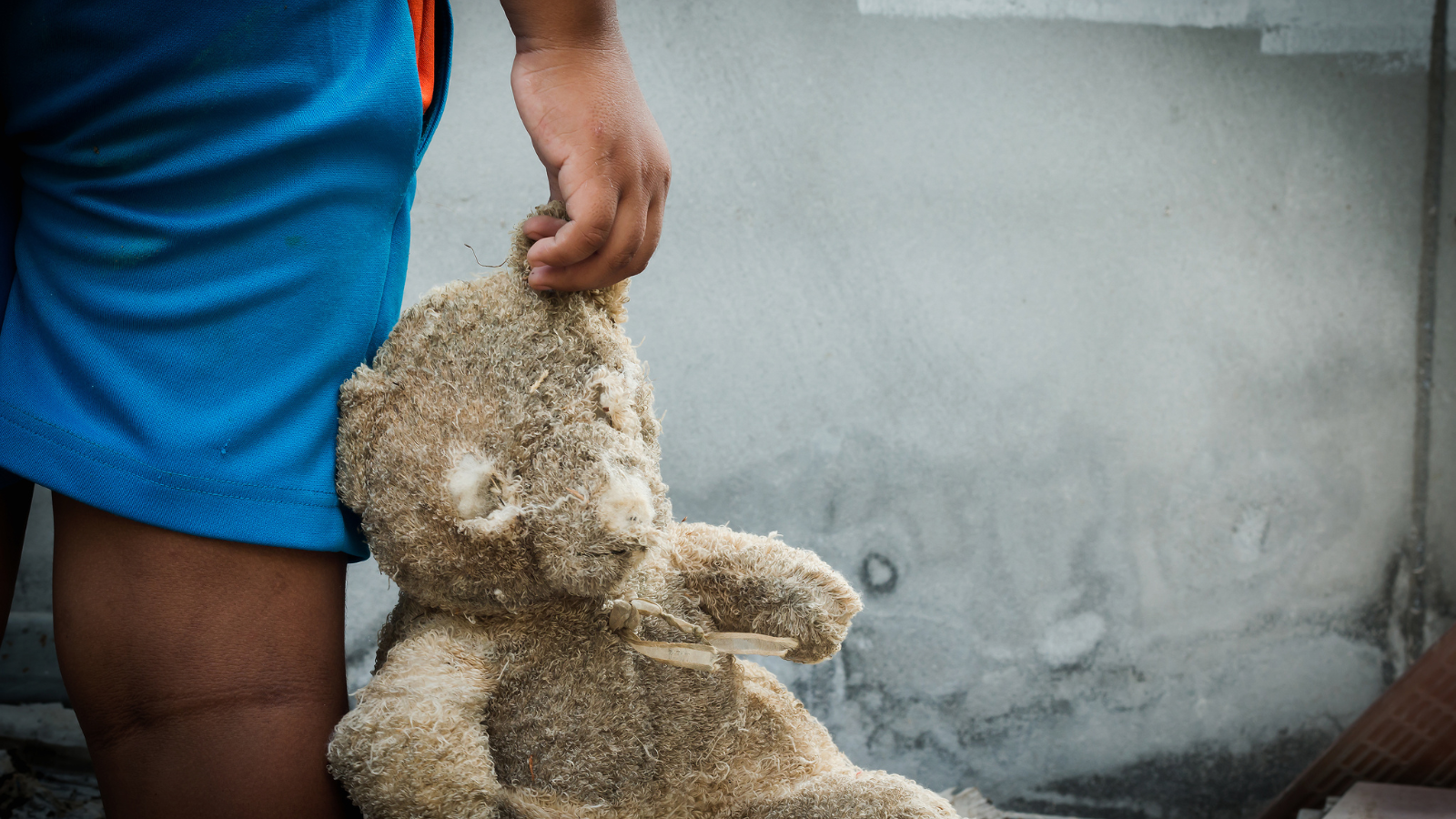 Child holding a worn teddy bear