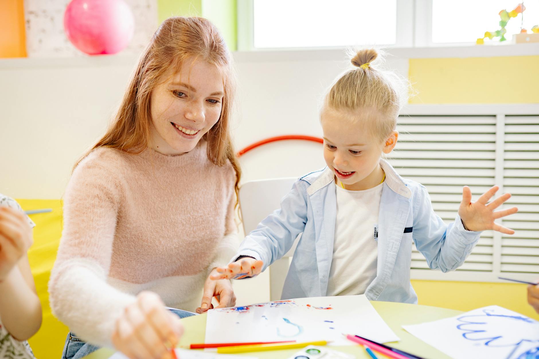 girl learning to paint with her teacher